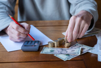 Close up man with calculator counting, making notes at home