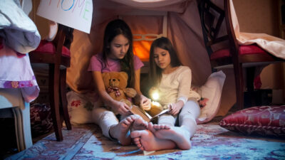 Two girls wearing pajamas in blanket fort