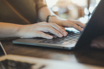 Closeup image of hands working and typing on laptop keyboard