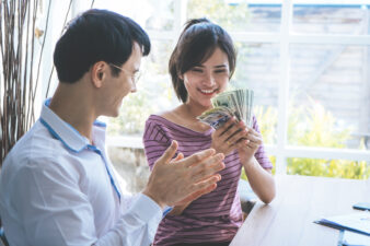 woman looking happy over a wad of cash