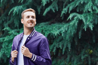 Happy man standing against trees