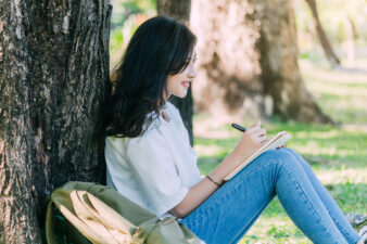 Woman leaning against a tree while journaling