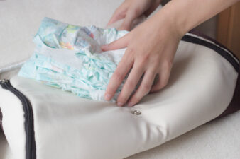 Female hands lay baby diapers in a bag