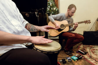 Two men playing the guitar and bongo drum