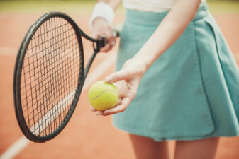 Close up of girl holding a tennis ball and racket