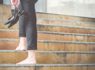 Woman walking up stairs holding high heels