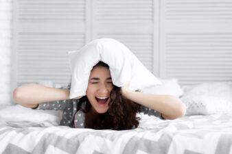 frustrated woman with a pillow over her ears