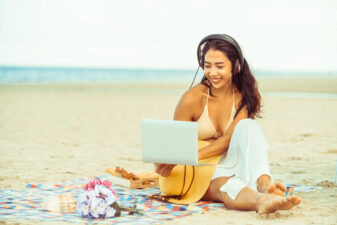 Young woman looking at her laptop on the beach