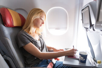 Blonde woman writing while sitting on an airplane