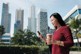 Woman holding coffee looking at phone