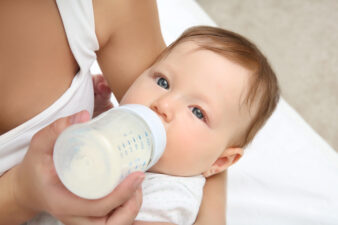 Mother holding and feeding baby from bottle