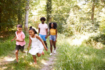 Black couple walking through forest with kids