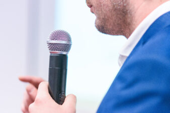 man in a blue suit speaking into a microphone