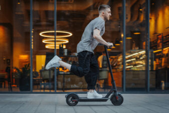 Man zipping down the sidewalk on a scooter