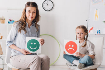 Woman and child holding happy and sad faces