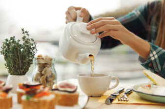 close up view of woman pouring tea from kettle into mug