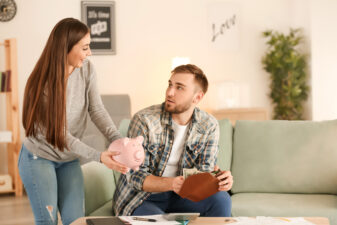 woman holding a piggy bank talking to a man