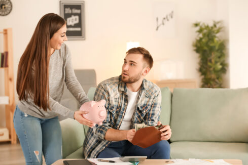 woman holding a piggy bank talking to a man