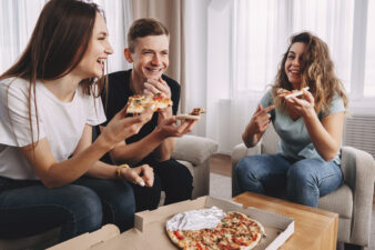 friends eating pizza and talking at home party