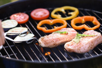 Cooking of juicy meat and vegetables on barbecue grill, closeup