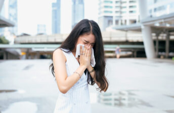 Woman blowing her nose on the street