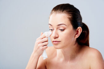 Young woman removing makeup from face