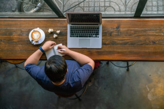 High angle view of man at his desk with laptop and cup of coffee