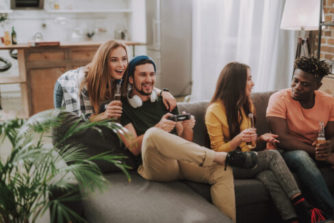 Young people chatting, playing video games and enjoying drinks