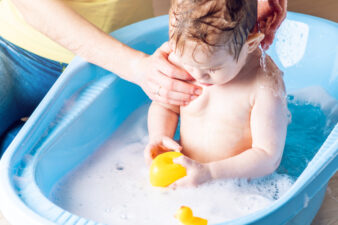 Mom washing baby in tub