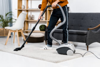 cropped view of man in modern living room cleaning house with hoover