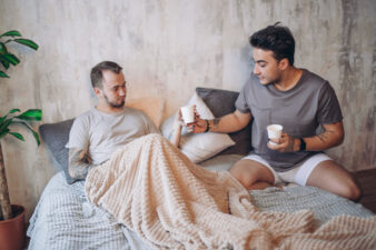 Man giving another man coffee in bed