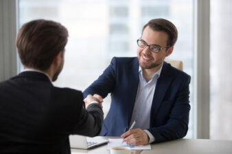 Smiling manager handshaking client applicant at meeting or job interview