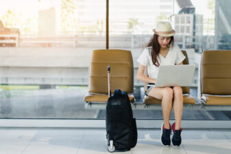 Woman sitting on her laptop with her luggage waiting on flight