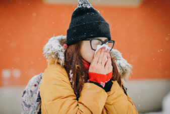 Woman blowing her nose into handkerchief. Young woman getting sick with flu