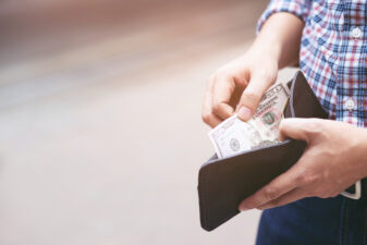 man holding an open wallet taking out cash