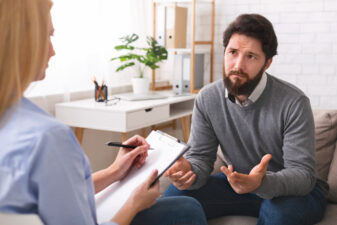 Man speaking with a therapist as she takes notes