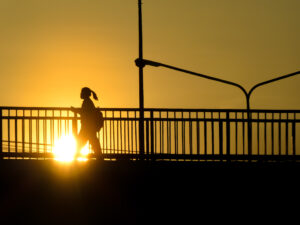 Silhouette of woman walking on a bridge during sunset