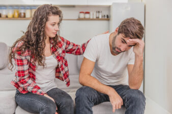 Woman comforting a man on couch