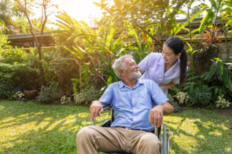 Happy nurse taking care of male patient in wheelchair