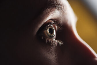 close up view of adult man eye with eyelashes and eyebrow looking away in dark