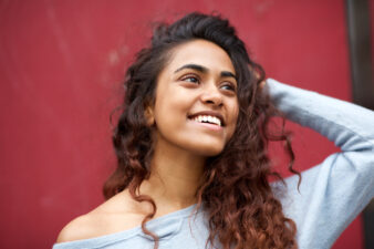 Curly haired woman touching her head against red background