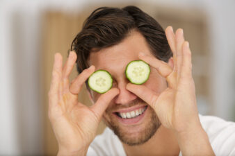 Goofy man holding cucumbers over his eyes