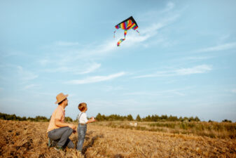 Father and son flying kite in open field