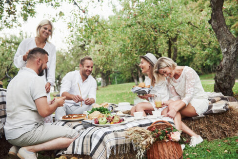 Group of people joking around outside at a picnic table