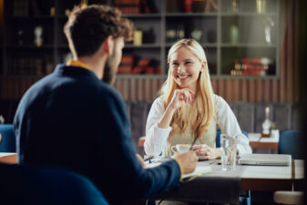 smiling blonde woman speaking with a brunette man