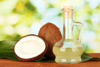 decanter with coconut oil and coconuts on green background