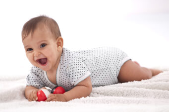 Laughing baby girl with small balls laying on the floor