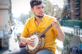 young man playing a banjo in an urban environment