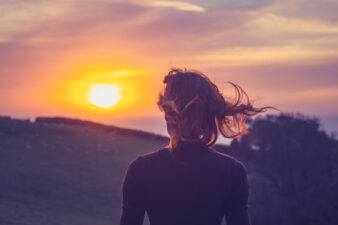 back view of woman looking out at the sunset