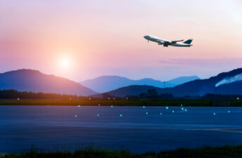 passenger plane fly up over take-off runway from airport at sunset